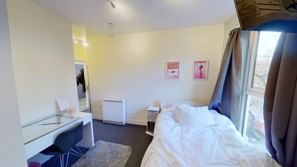 Bright single bedroom with a large window, fitt...