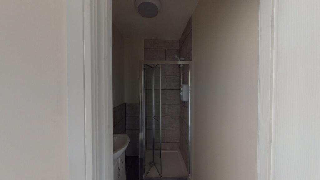Narrow bathroom with a tiled walk-in shower, si...