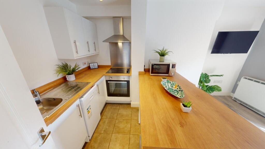 Bright, modern galley kitchen with white cabine...
