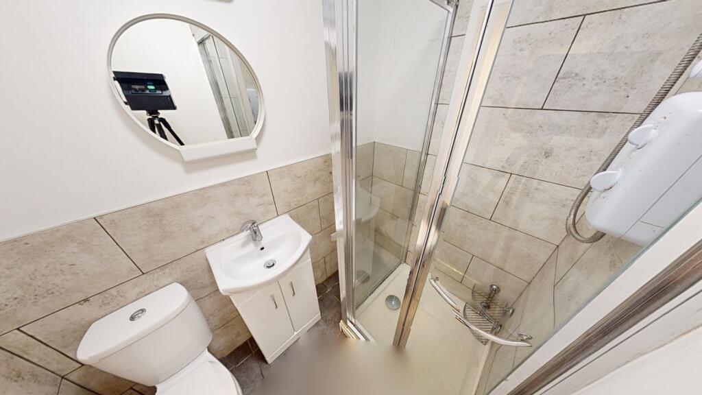 Modern tiled bathroom with a corner glass showe...