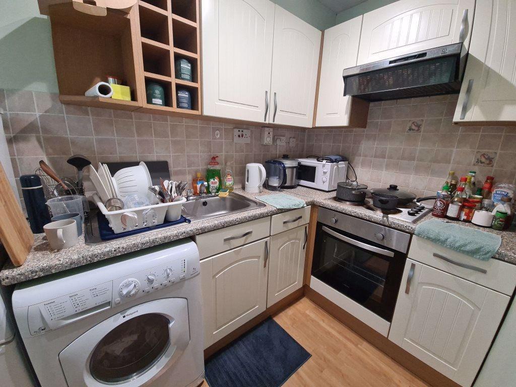 A compact kitchen area with white cabinetry, a ...