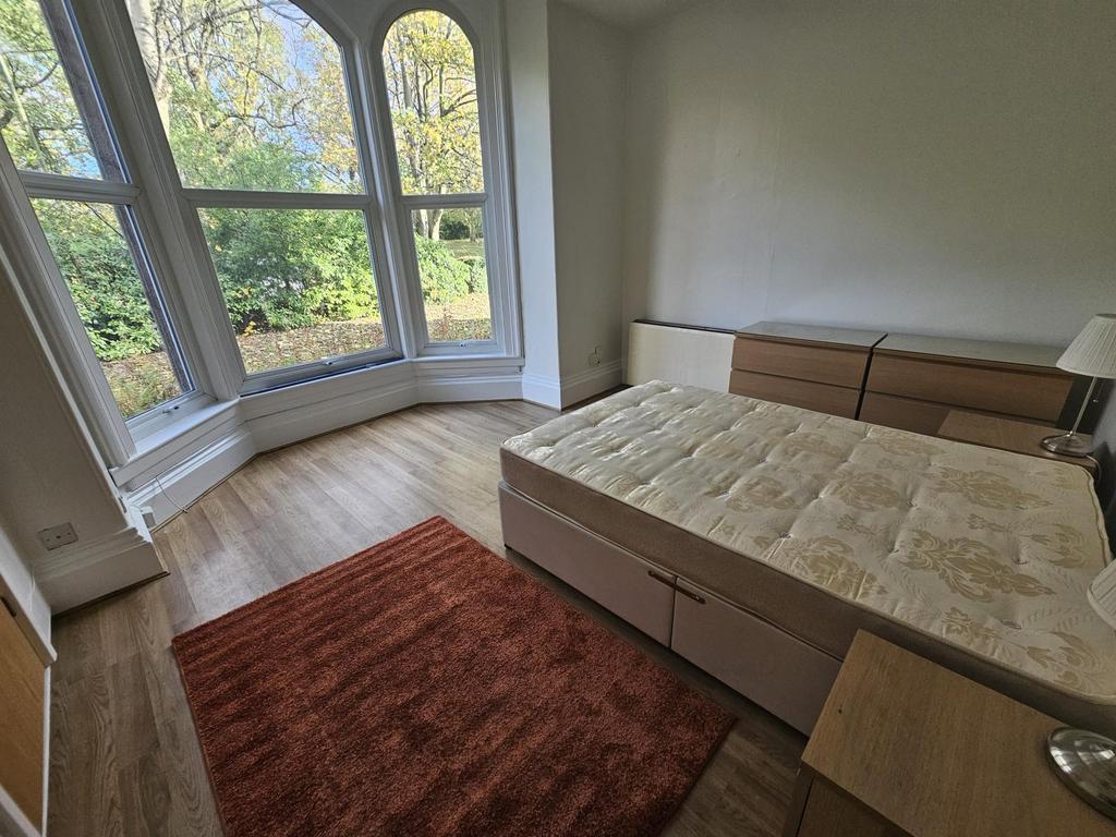 A bright, sunny bedroom featuring a large windo...