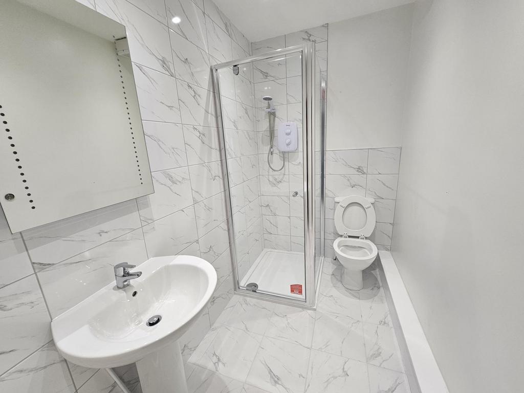 A clean, modern bathroom with a walk-in shower,...