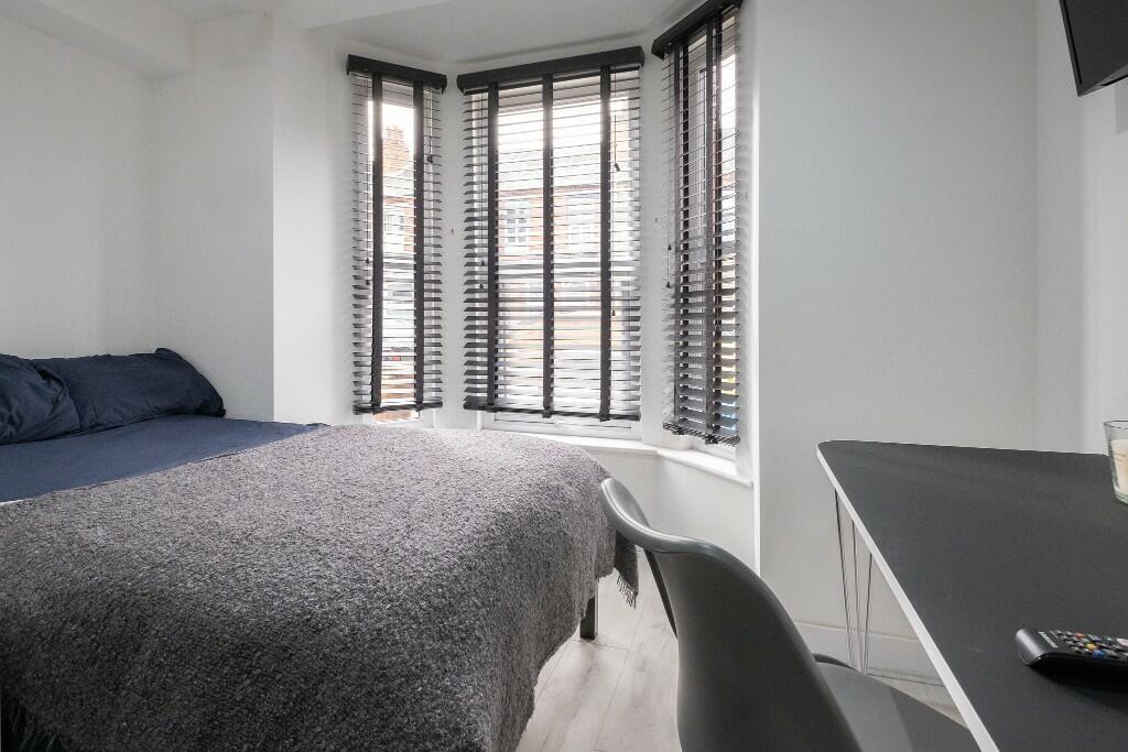 A bright and tidy single bedroom featuring a co...