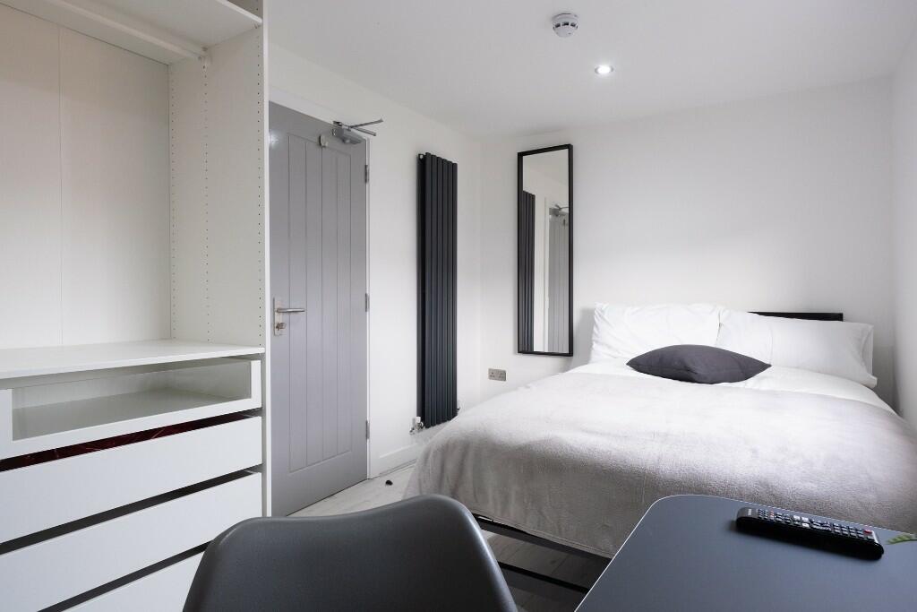 A clean and well-lit bedroom featuring a comfor...