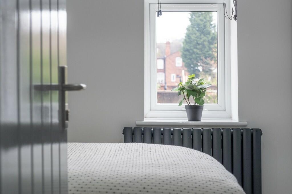 A bright and tidy bedroom featuring a large win...