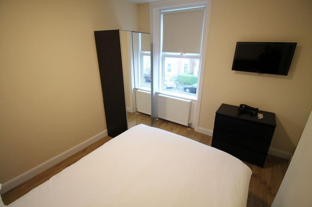 A bright, tidy bedroom featuring a large bed an...