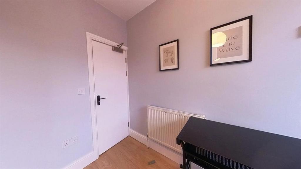 Small, tidy bedroom with pale walls, wood-effec...