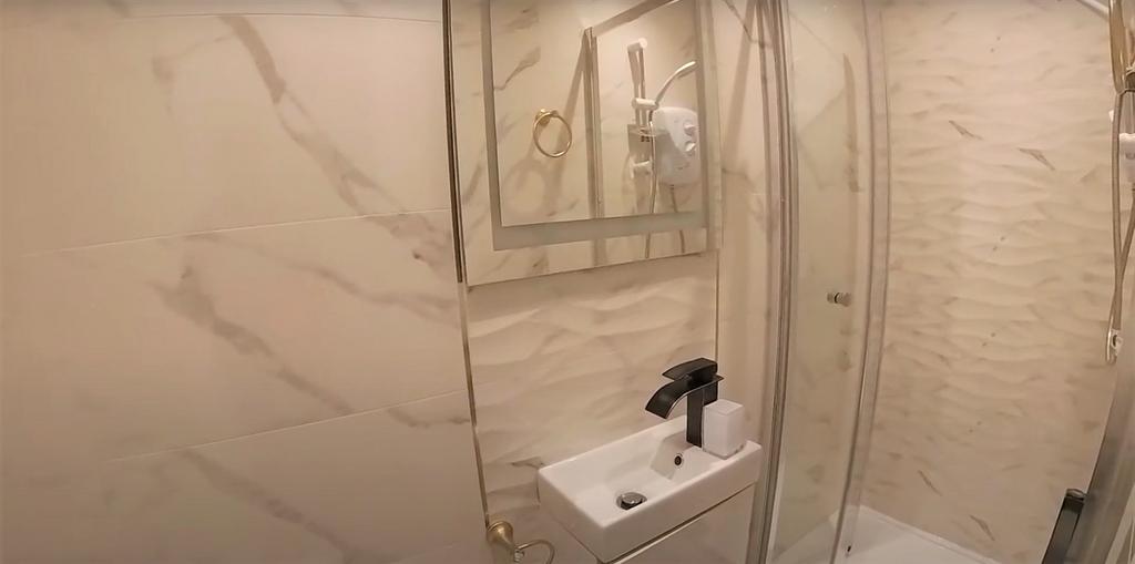 A modern bathroom featuring a spacious shower a...