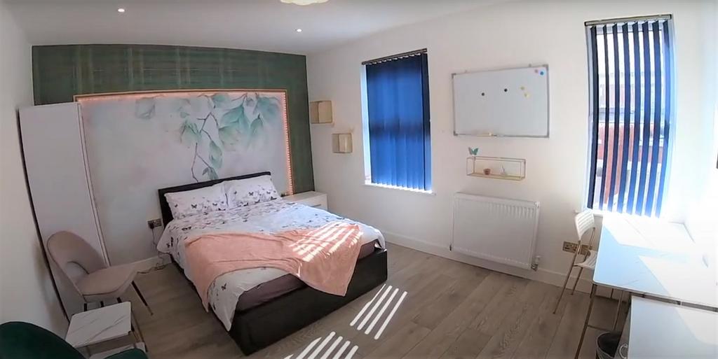 A well-lit bedroom featuring a double bed with ...