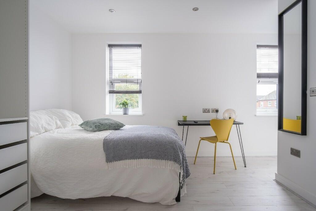 A bright and modern bedroom featuring two large...