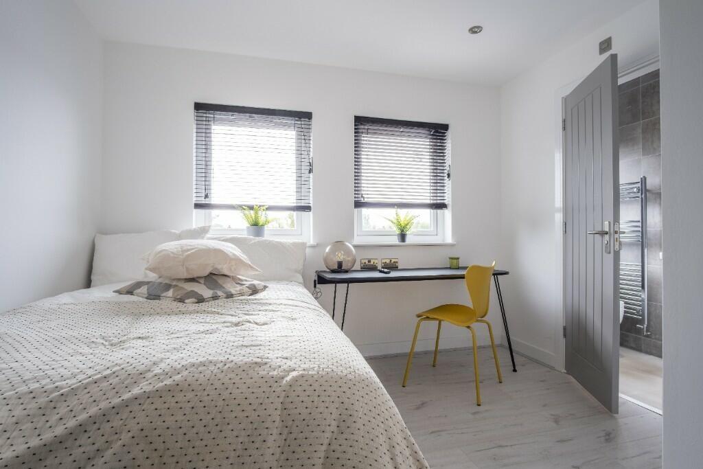 A bright and inviting bedroom featuring two lar...