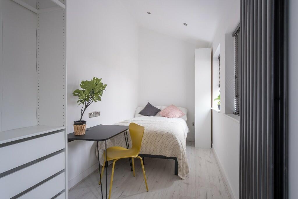 A bright, clean bedroom with a comfortable bed,...