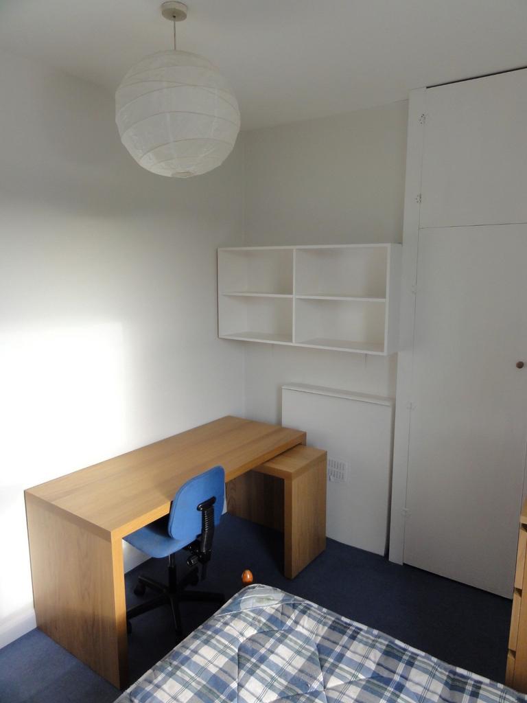 A cozy student bedroom featuring a simple woode...