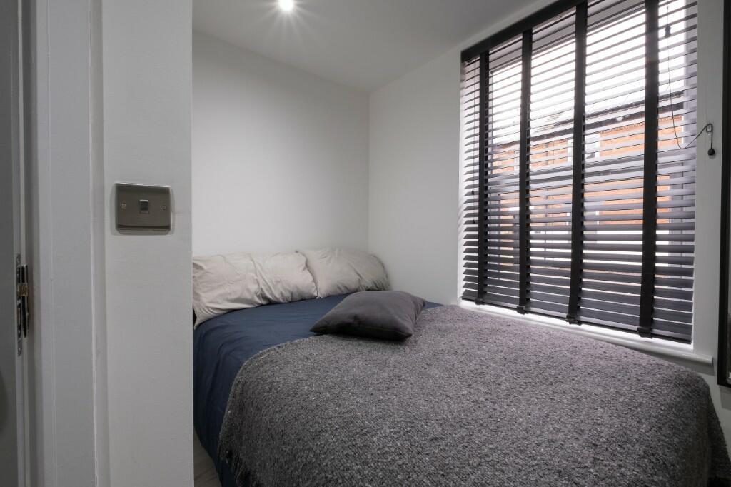 Neat, simply furnished bedroom with a made bed,...