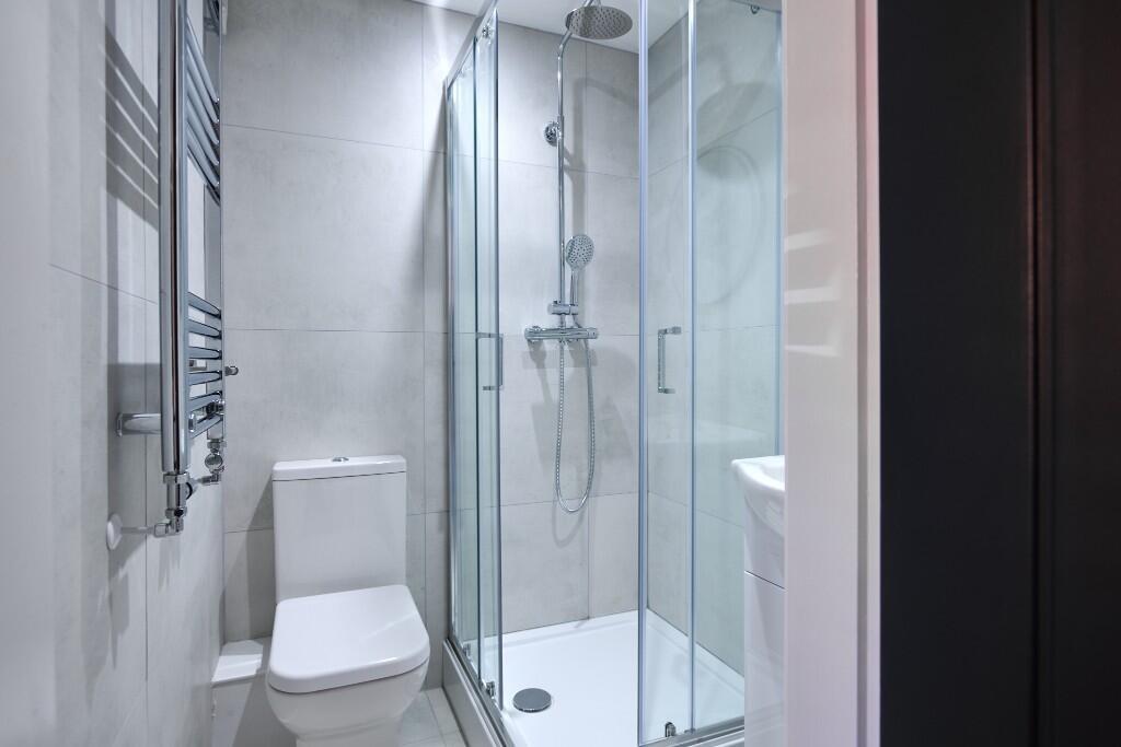 Modern tiled bathroom with a glass-enclosed sho...