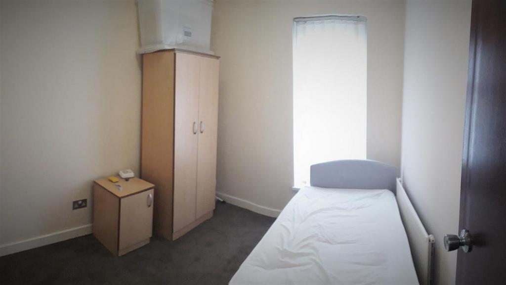 A modest single bedroom featuring a neatly made...