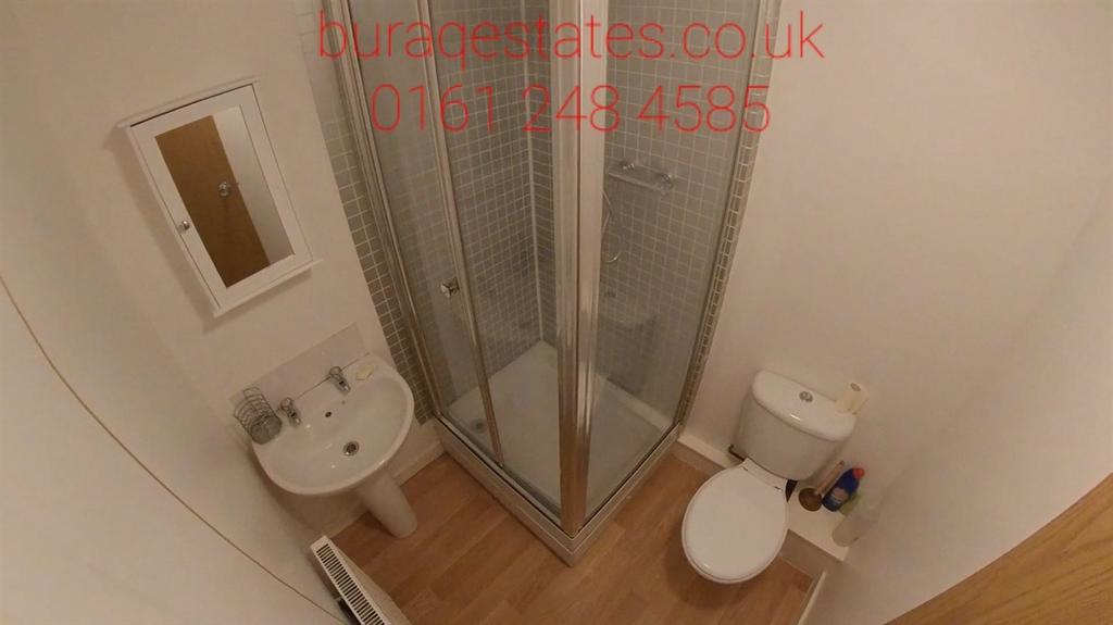 Clean compact bathroom with a corner shower cub...