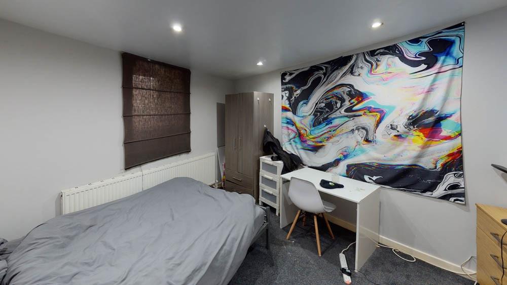 A well-lit bedroom featuring a comfortable doub...