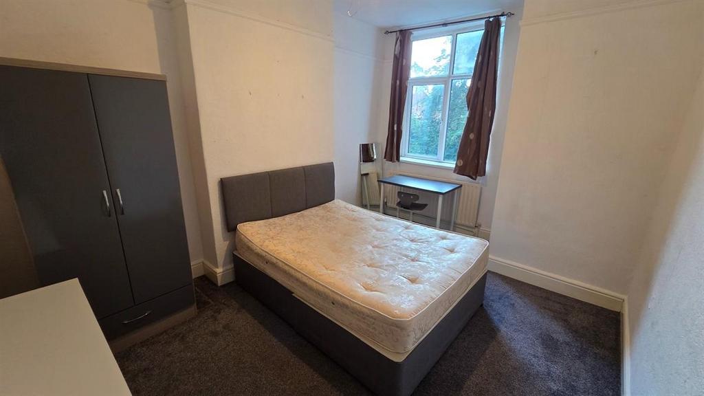 Bright, simply furnished bedroom with a double ...
