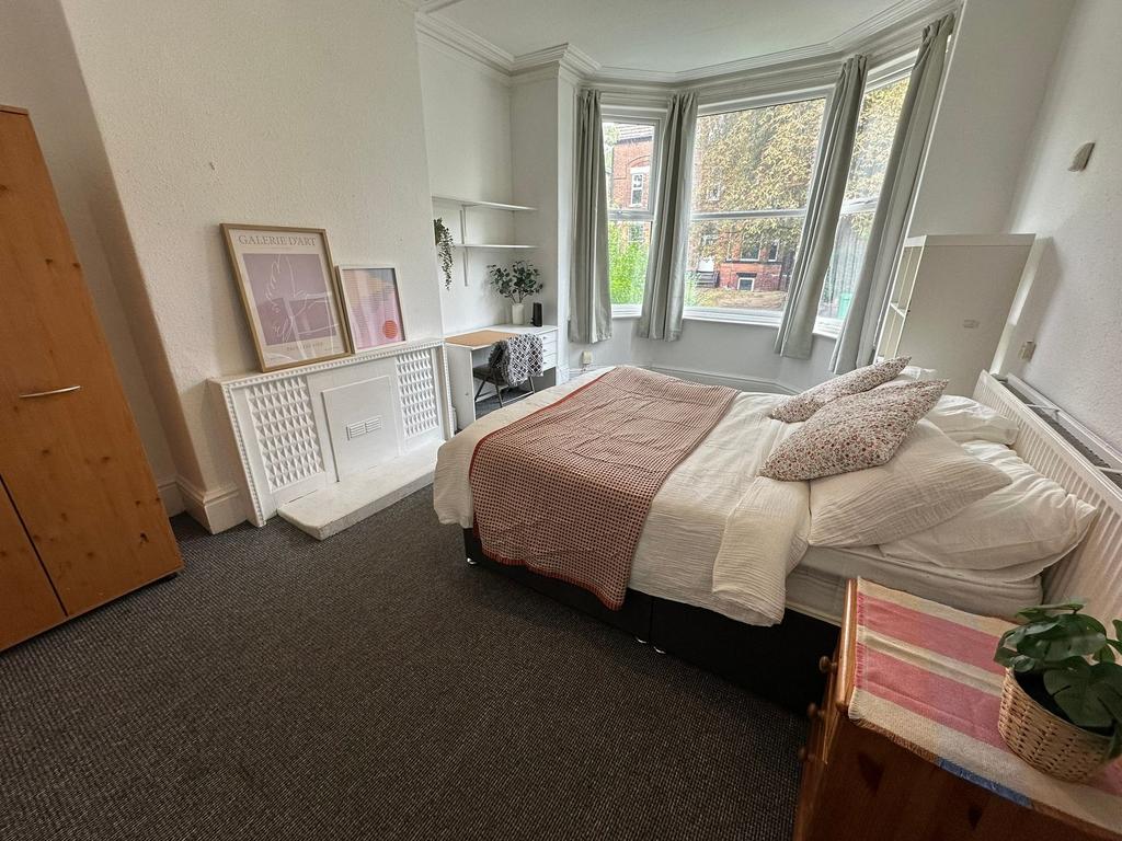 A bright and welcoming bedroom with a large bay...