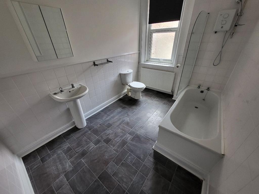 A bright, clean bathroom featuring a bathtub, t...