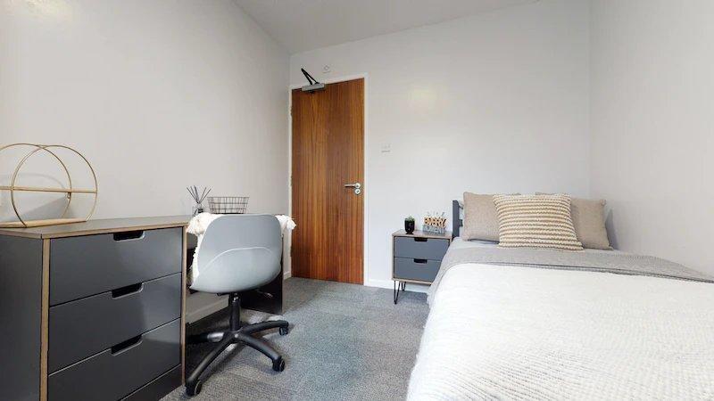 A bright and tidy bedroom featuring a comfortab...