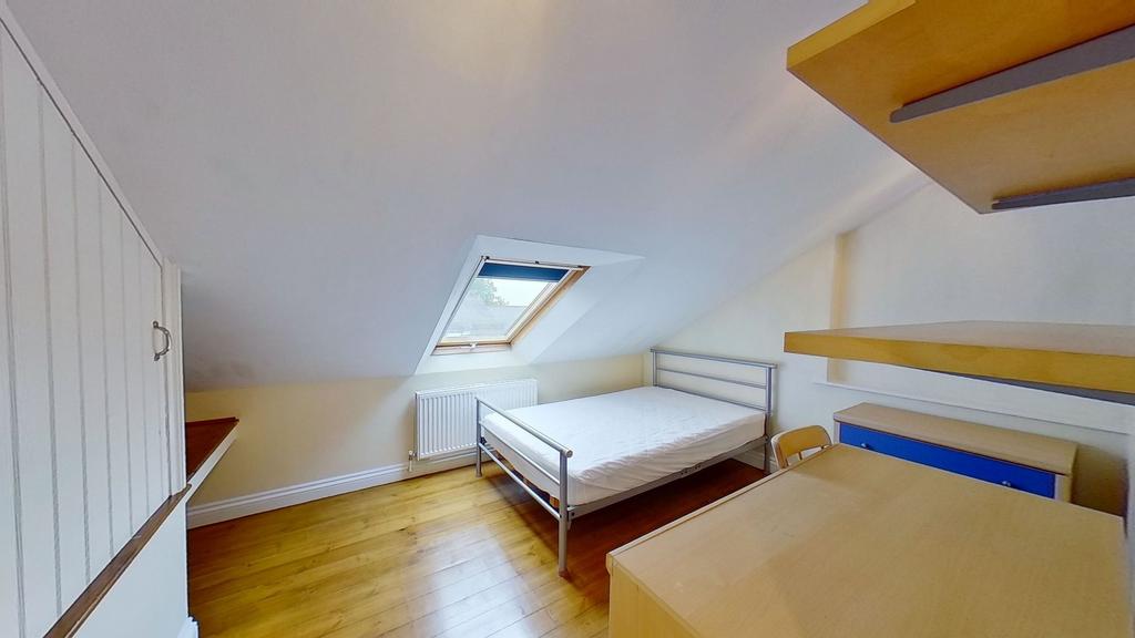 Bright attic double bedroom with a metal bed fr...