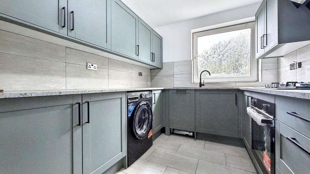 Modern galley kitchen with muted green cabinetr...