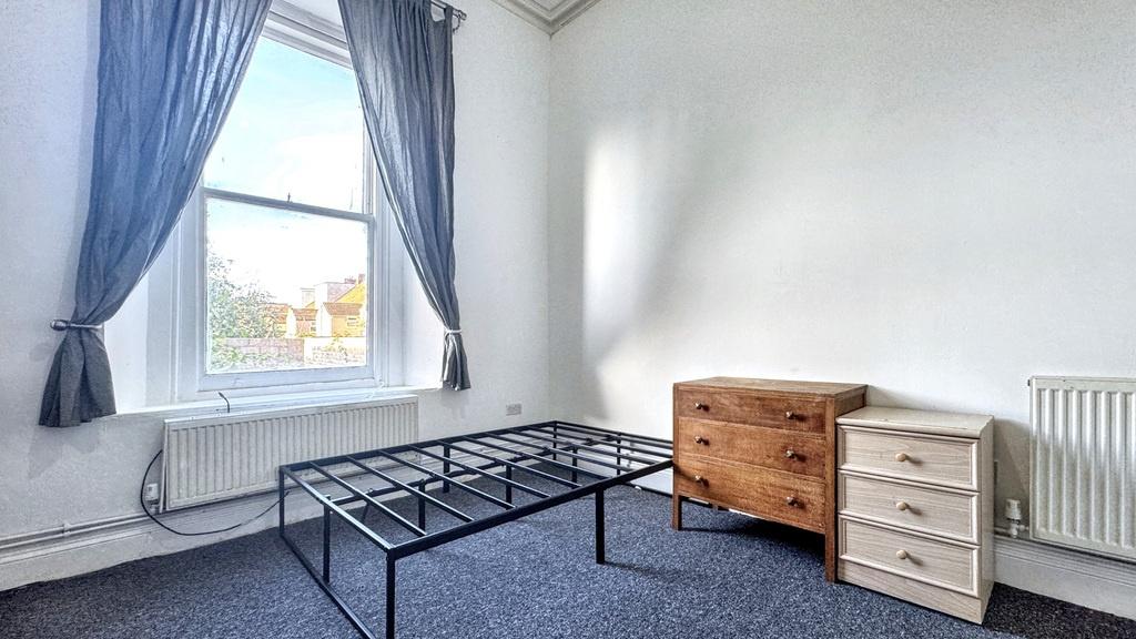 Bright, simply furnished bedroom with a large w...
