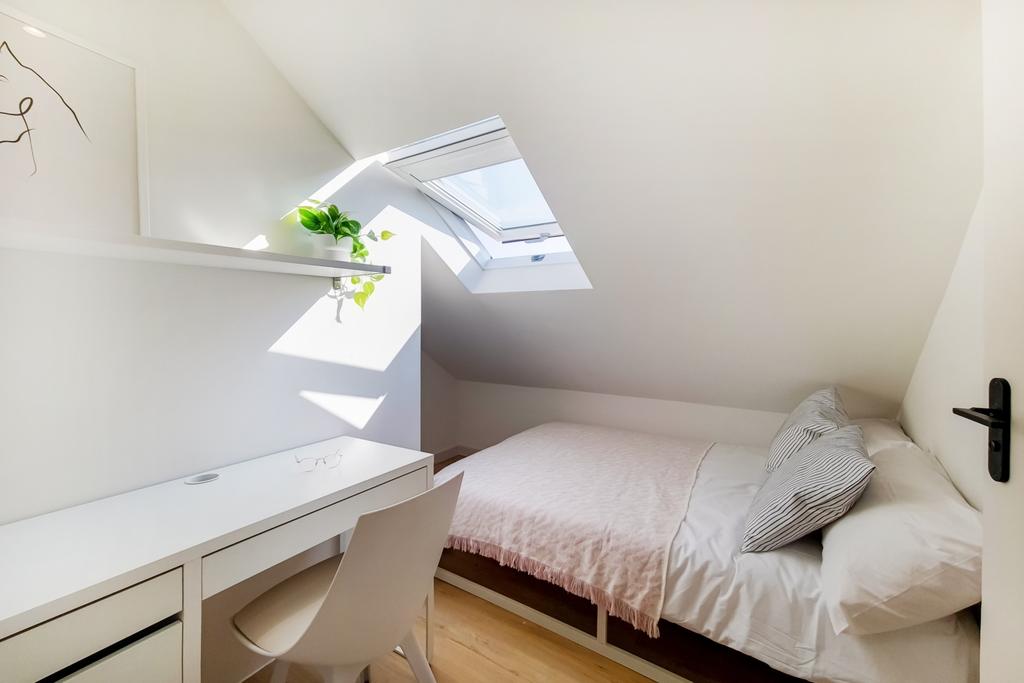 A bright, cozy bedroom featuring a comfortable ...