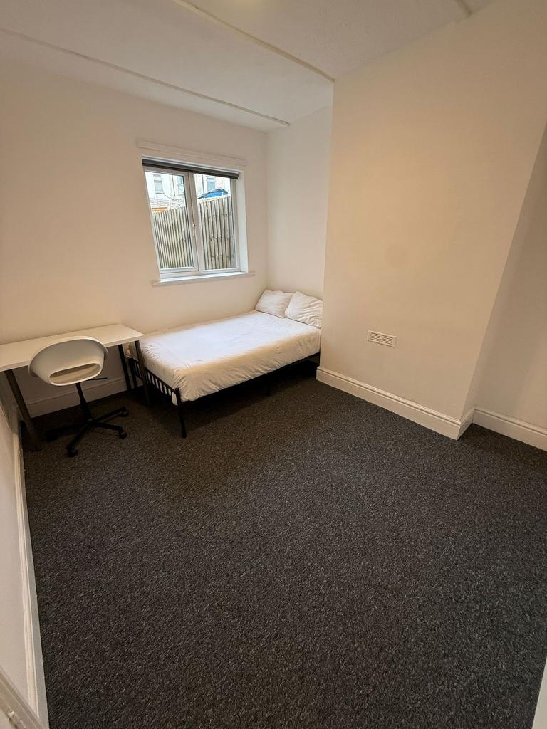 A cozy single bedroom featuring a comfortable b...