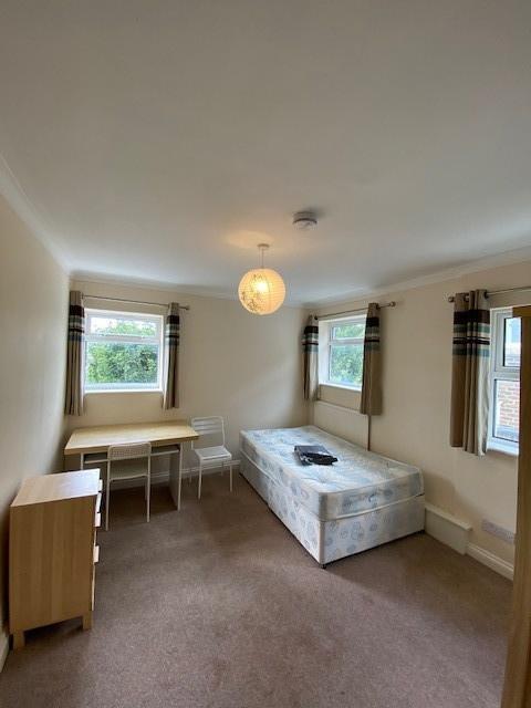 A well-lit bedroom with two windows providing n...