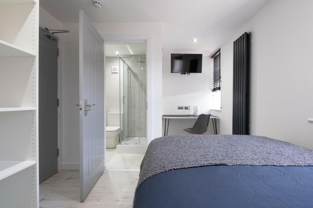 A modern, clean single bedroom featuring a comf...