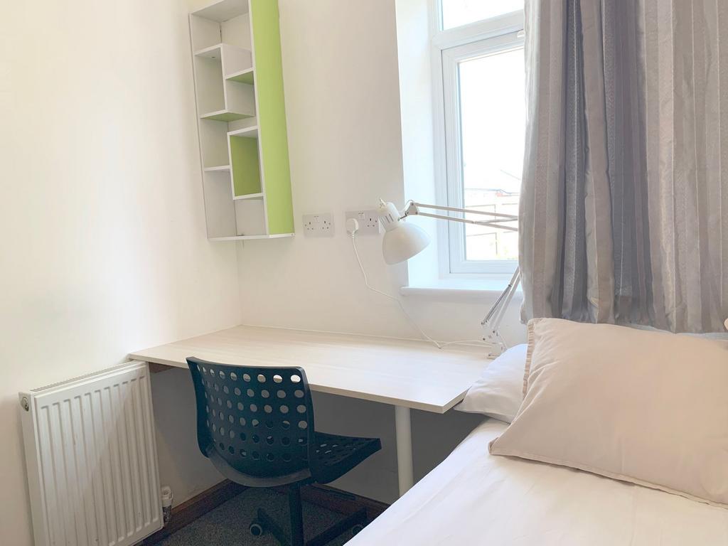 Bright and tidy single bedroom corner with a wh...