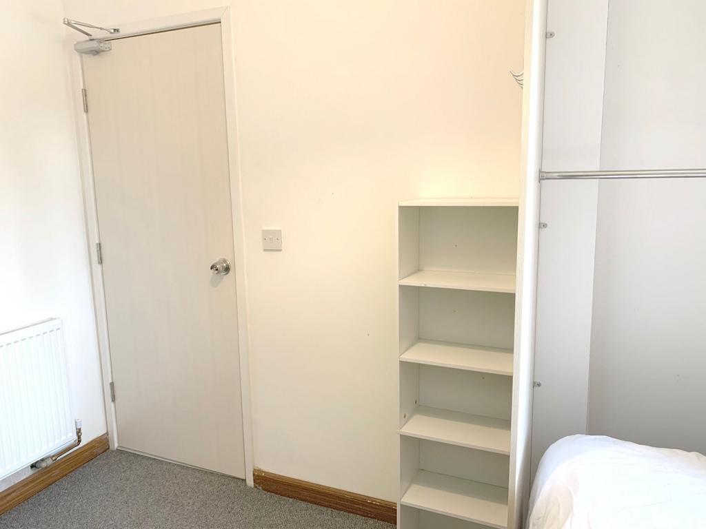 A clean and bright single bedroom featuring whi...