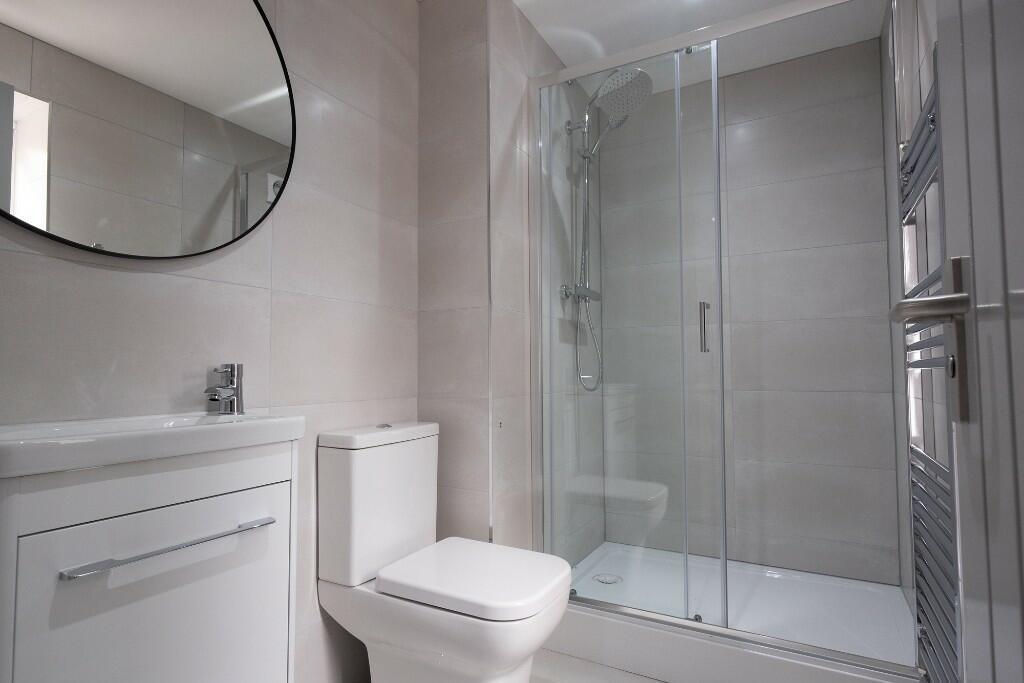 Modern tiled bathroom featuring a walk-in glass...