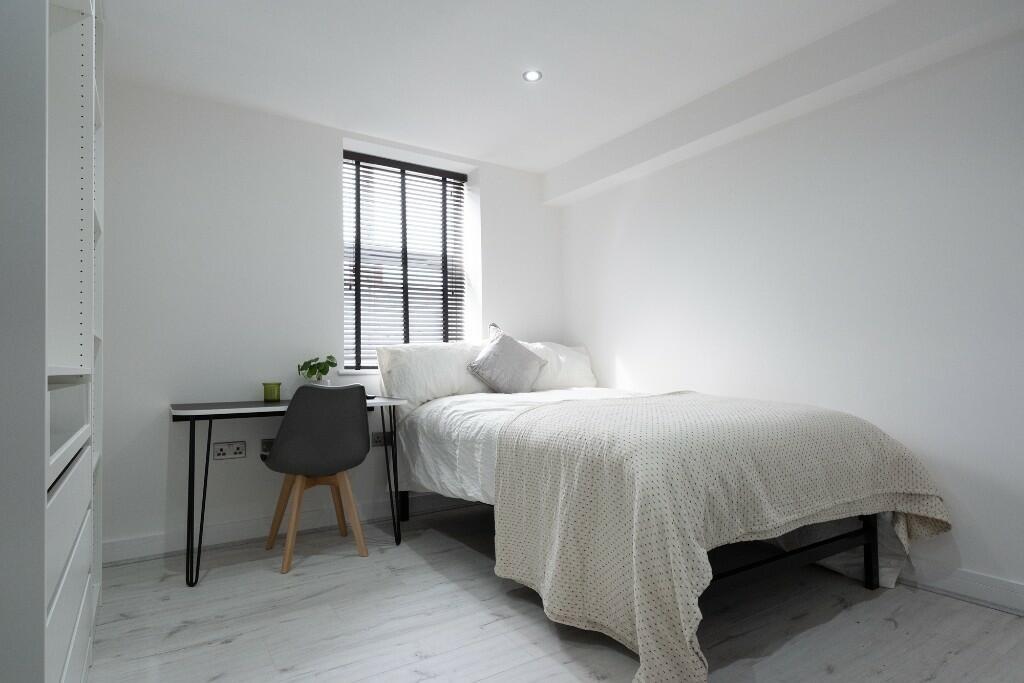 Bright, simply furnished bedroom with a neat si...