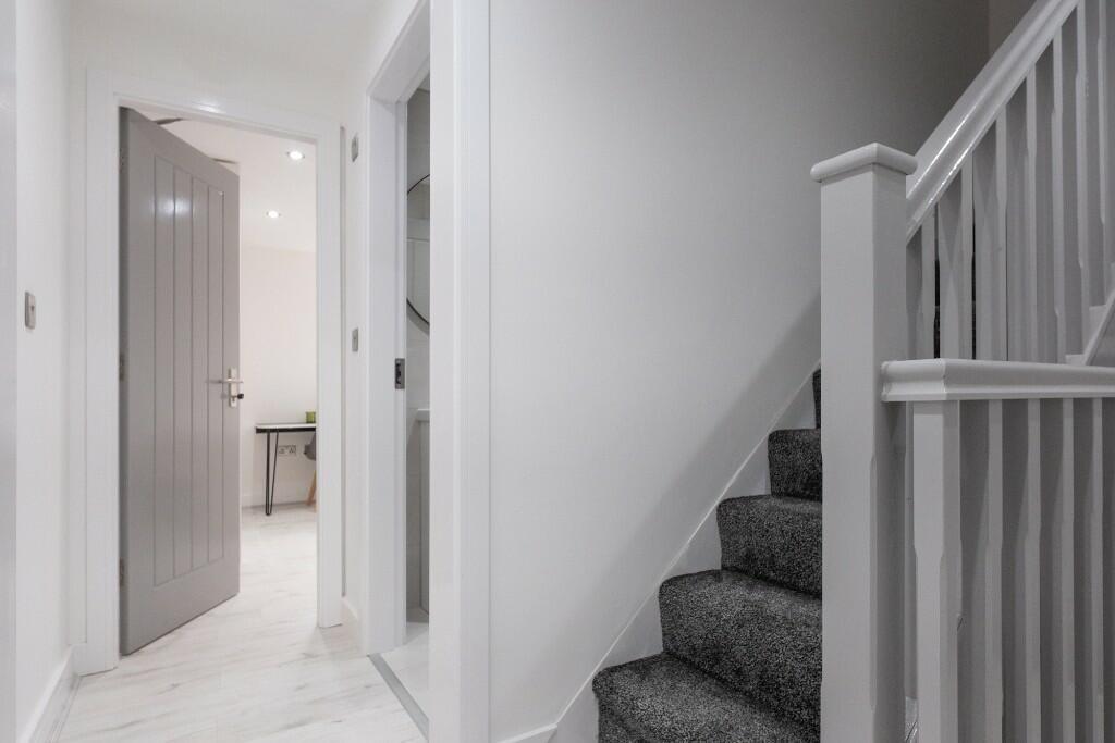 Bright, modern hallway with neutral decor, carp...