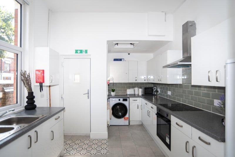 Bright, modern galley kitchen with white fitted...