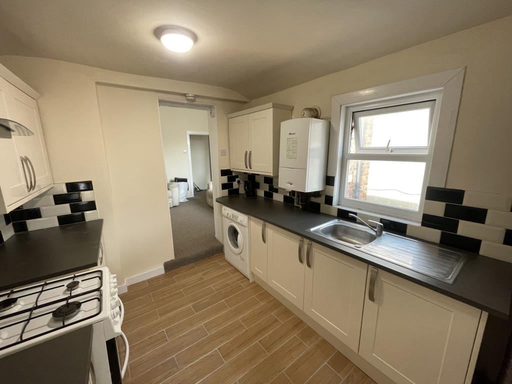 Modern galley kitchen with cream cabinetry, bla...