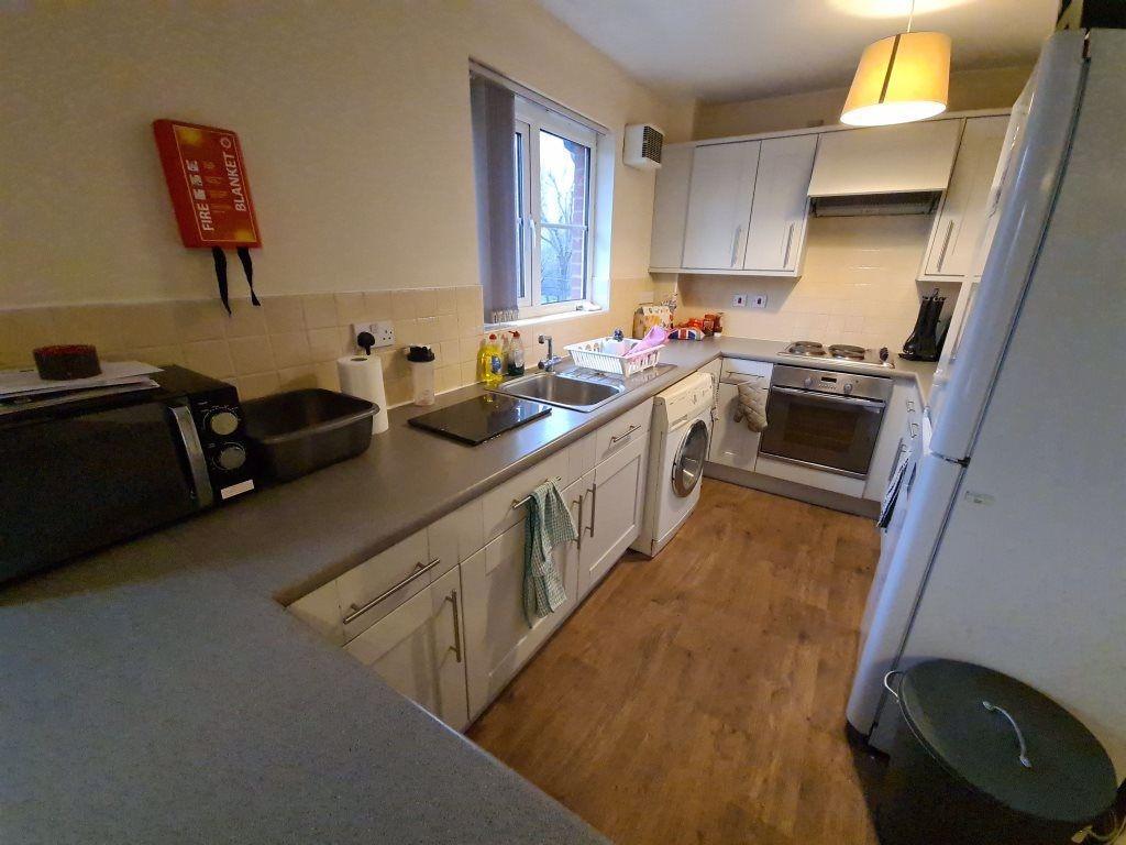Bright galley-style kitchen with white cabinetr...