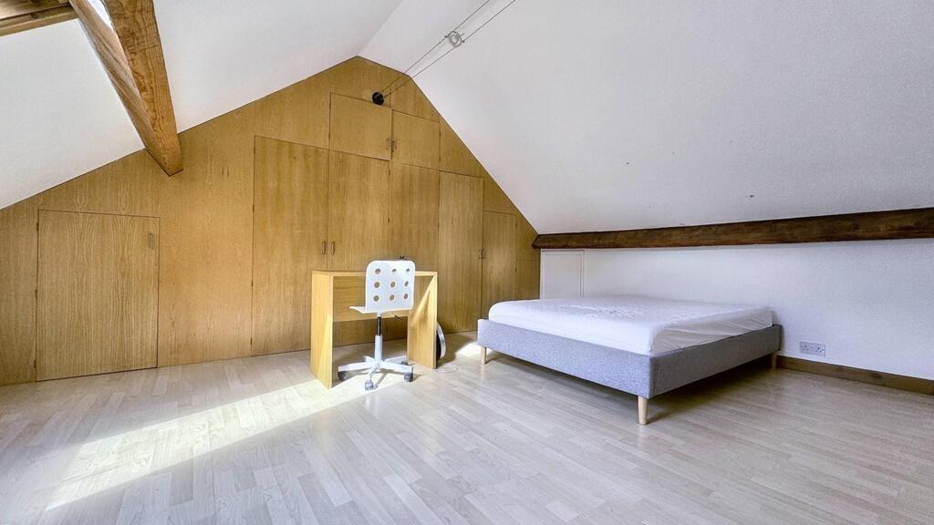 Bright, minimalist loft bedroom with exposed be...