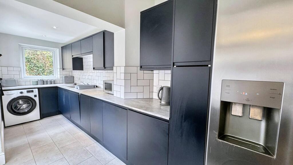Modern galley kitchen with sleek dark cabinetry...
