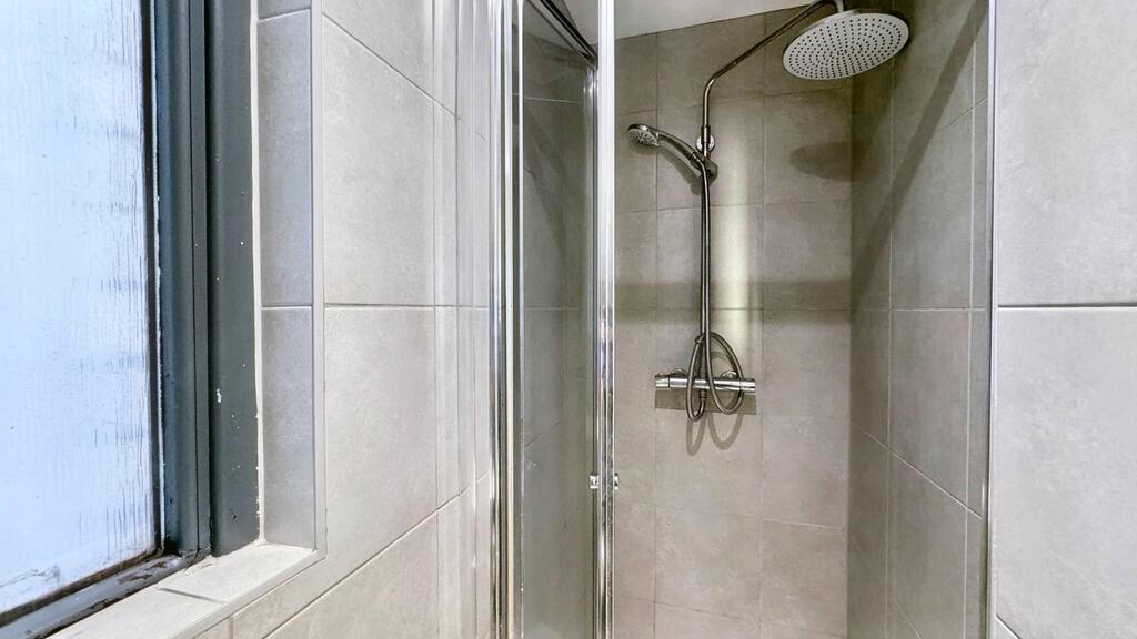 Modern tiled bathroom with a glass-enclosed sho...