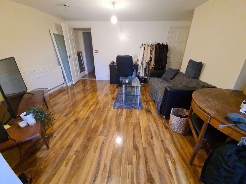 Spacious, open-plan living area with warm wood-...