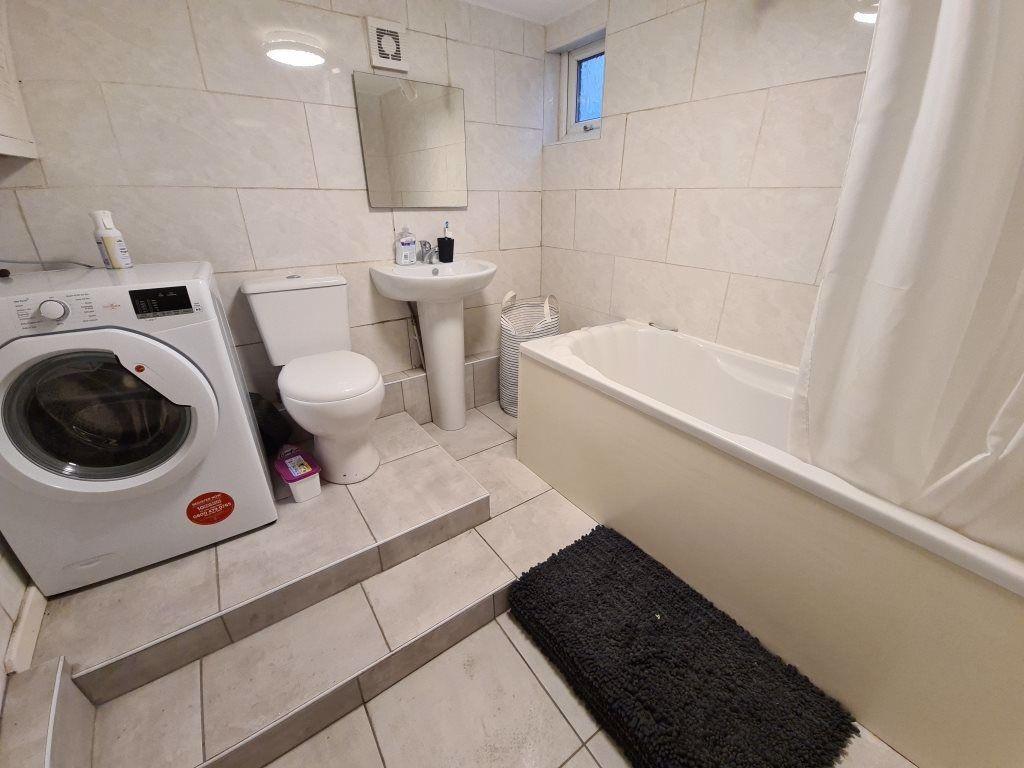 Bright, tiled bathroom with a bathtub and separ...
