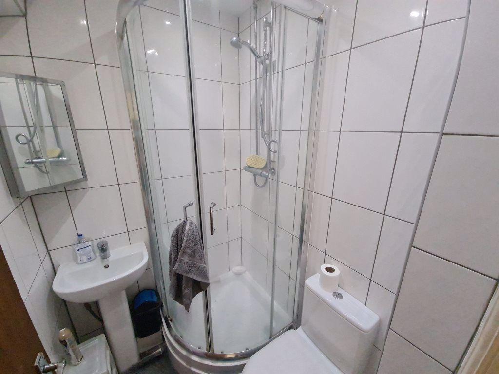Bright, modern tiled bathroom with a corner gla...
