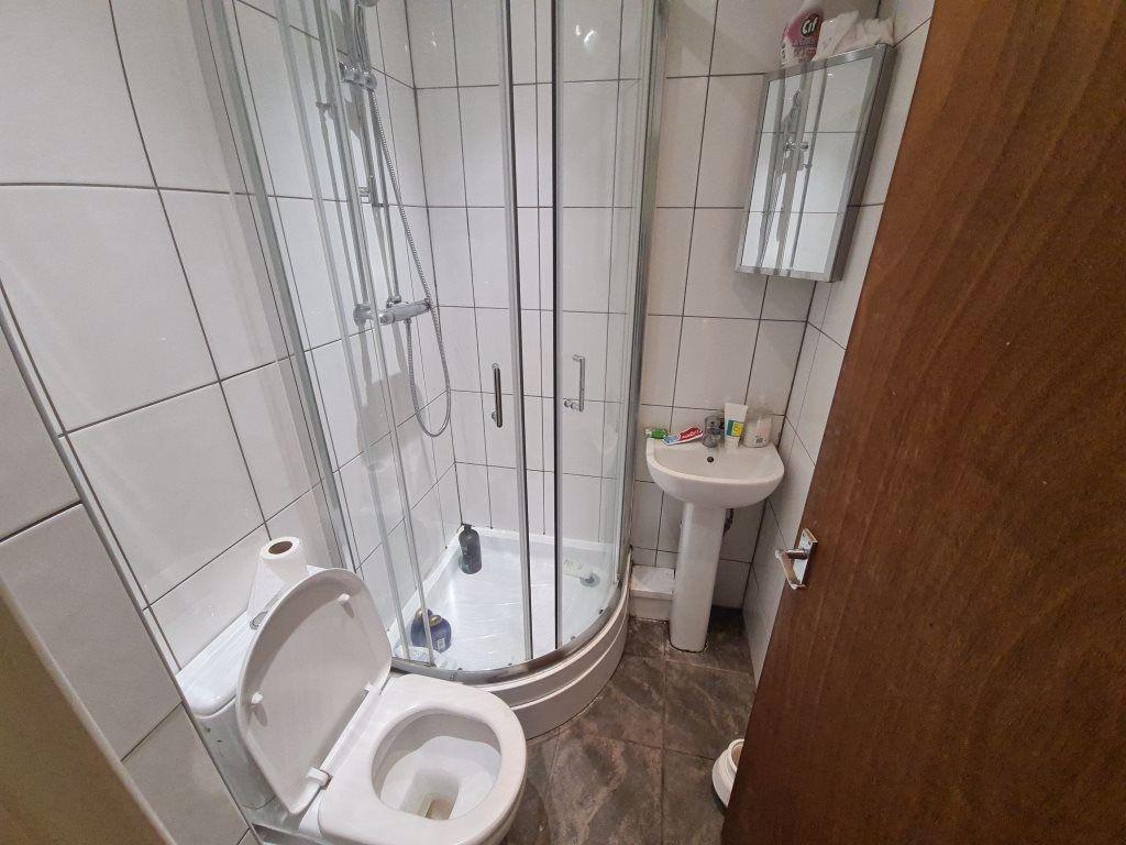 Bright tiled bathroom with a corner glass showe...