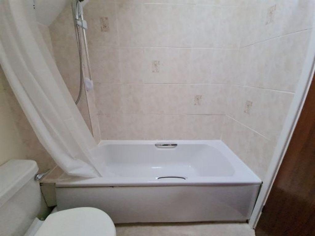 Bright, clean bathroom with a full bathtub and ...